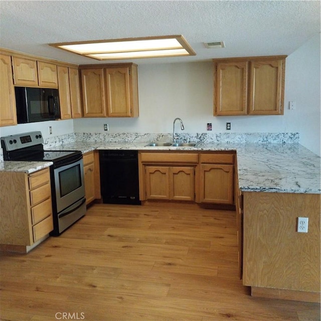 kitchen with sink, light hardwood / wood-style flooring, black appliances, light stone countertops, and a textured ceiling