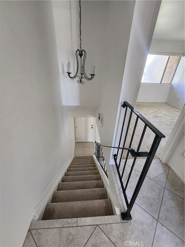 stairway with an inviting chandelier and tile patterned flooring