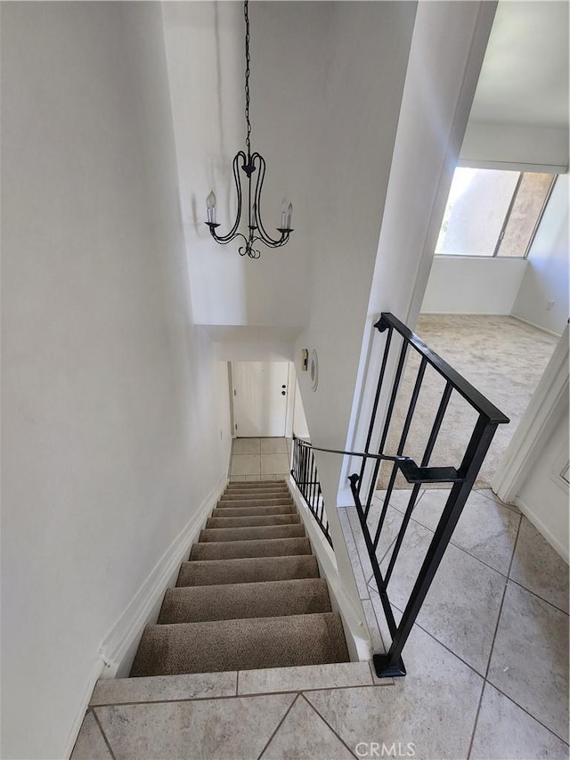 staircase featuring tile patterned floors, baseboards, and a chandelier