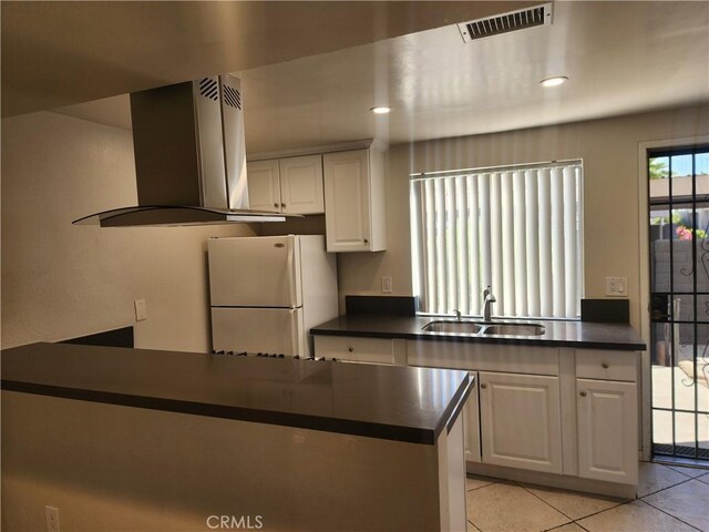 kitchen with sink, island range hood, white cabinets, and white fridge