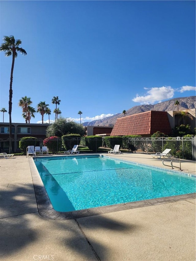 pool featuring a mountain view, a patio, and fence