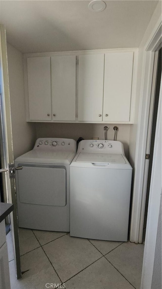 laundry area featuring light tile patterned floors, cabinets, and washing machine and clothes dryer