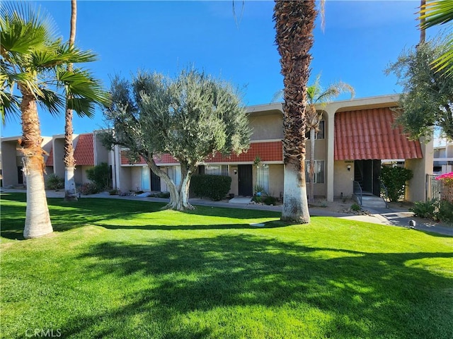 view of front of home with stucco siding, a front yard, and a tile roof