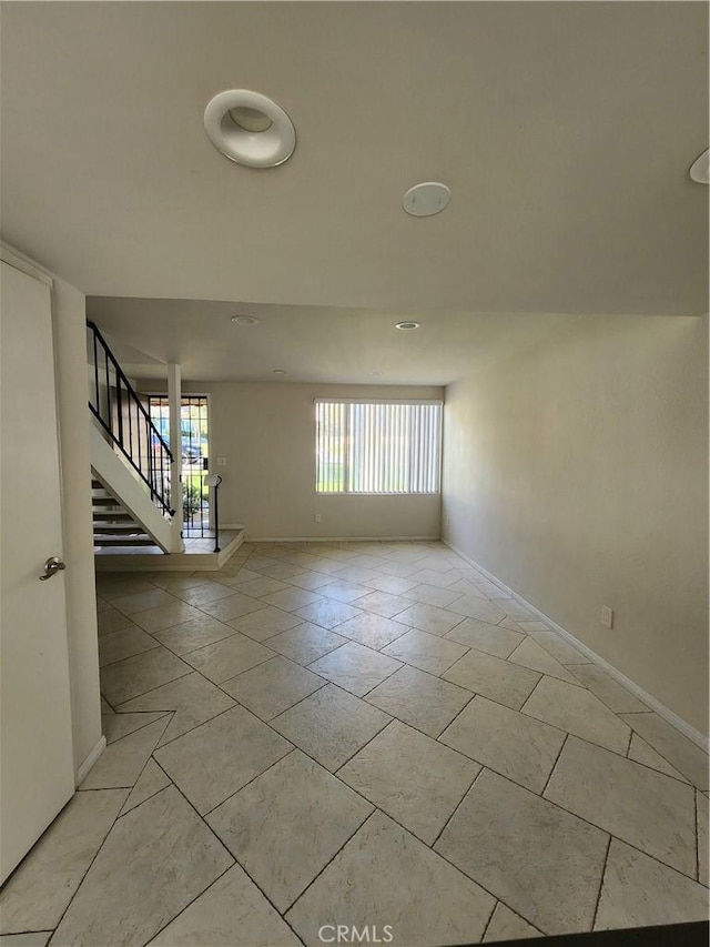 spare room featuring stairs and baseboards