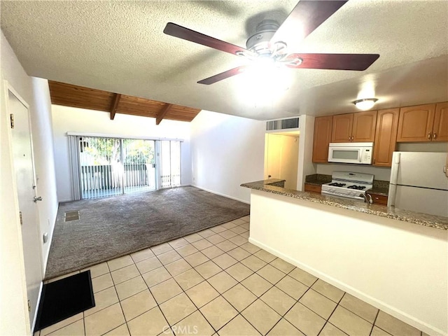 kitchen with vaulted ceiling with beams, white appliances, a textured ceiling, and light tile patterned flooring