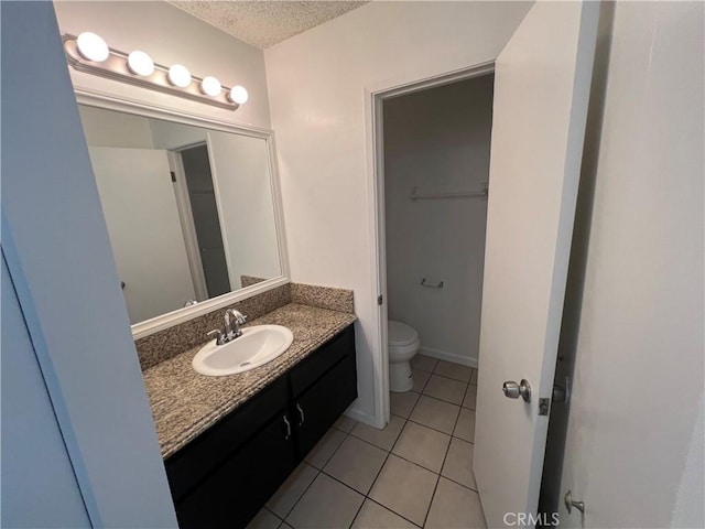 bathroom featuring tile patterned flooring, vanity, toilet, and a textured ceiling