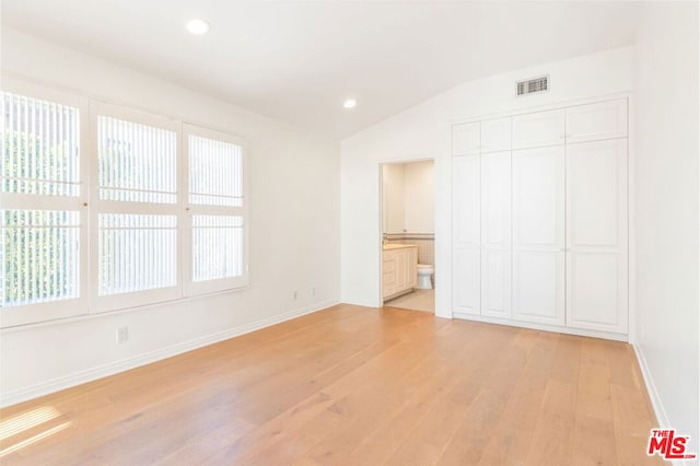 unfurnished bedroom with light hardwood / wood-style floors, multiple windows, a closet, and ensuite bath