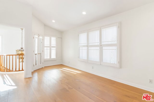 unfurnished room with light hardwood / wood-style floors and lofted ceiling