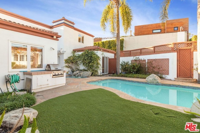 back of property featuring exterior kitchen and a patio