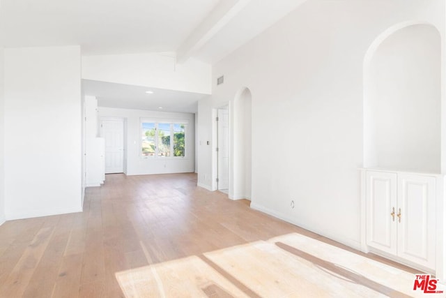 empty room featuring light hardwood / wood-style flooring and vaulted ceiling with beams