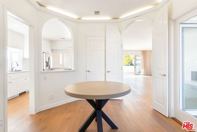 corridor with light hardwood / wood-style floors, sink, and ornamental molding