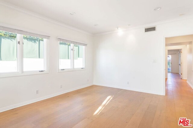 unfurnished room featuring light hardwood / wood-style flooring, ornamental molding, and a healthy amount of sunlight