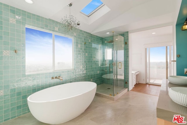 bathroom featuring tile walls, tile patterned flooring, lofted ceiling with skylight, vanity, and separate shower and tub