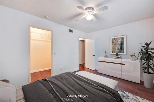 bedroom featuring dark hardwood / wood-style flooring, a spacious closet, a closet, and ceiling fan