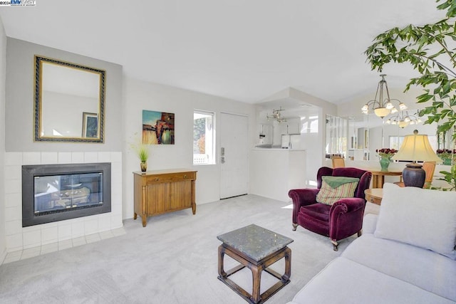 carpeted living room featuring a tiled fireplace and an inviting chandelier