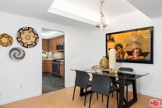 dining space with a tray ceiling, an inviting chandelier, and dark wood-type flooring