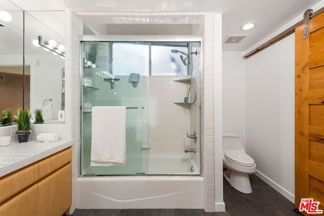 full bathroom featuring shower / bath combination with glass door, hardwood / wood-style floors, vanity, and toilet