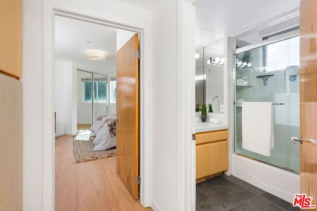 bathroom featuring hardwood / wood-style floors, vanity, and shower / bath combination with glass door