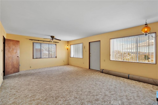 carpeted empty room with a wealth of natural light and ceiling fan