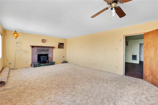 unfurnished living room with carpet flooring, ceiling fan, a wood stove, and heating unit