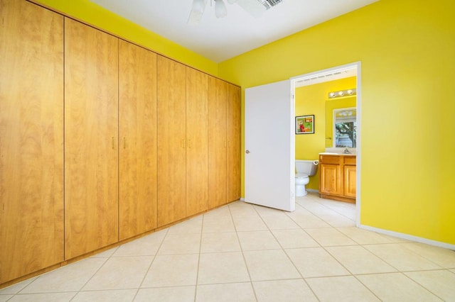 unfurnished bedroom featuring ceiling fan, ensuite bath, sink, and light tile patterned floors