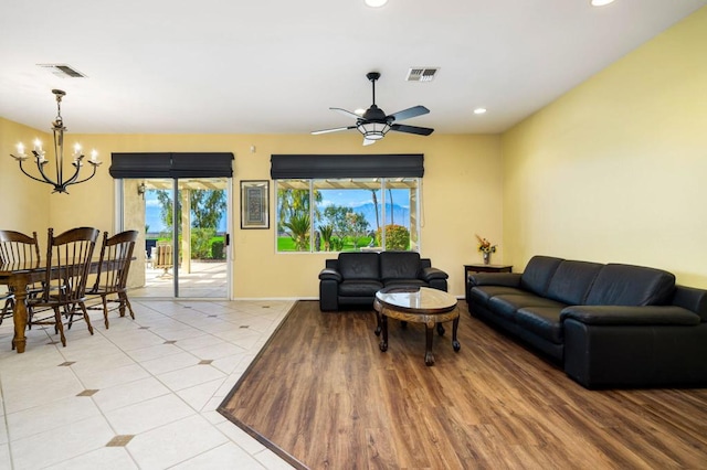 living room featuring light tile patterned floors and ceiling fan with notable chandelier