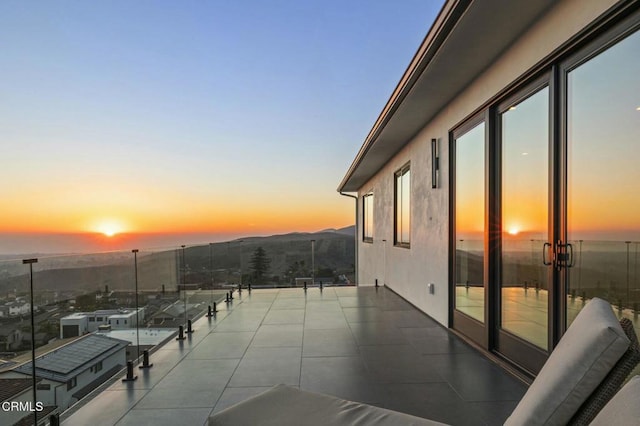 patio terrace at dusk with a mountain view and a balcony