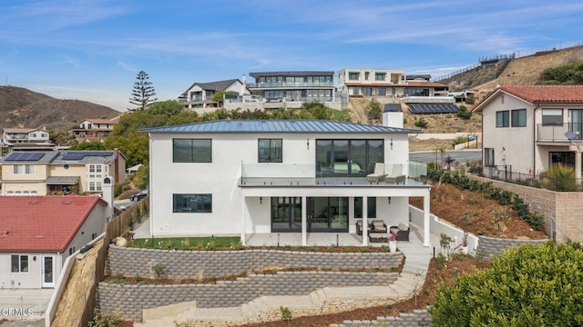 rear view of property featuring a mountain view, a patio, and a balcony