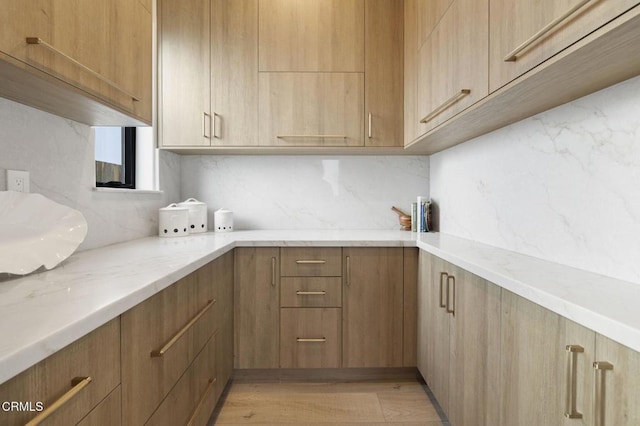 kitchen with light hardwood / wood-style floors, light stone countertops, and tasteful backsplash