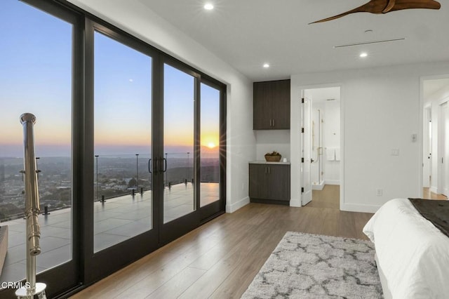 bedroom featuring french doors, light wood-type flooring, ensuite bathroom, access to outside, and ceiling fan