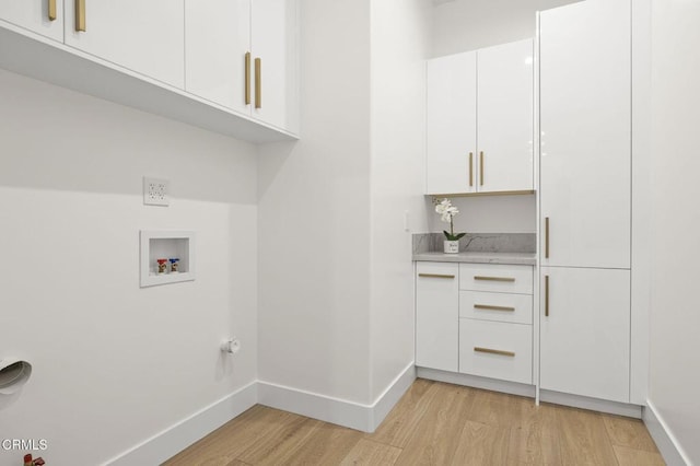 laundry area with light hardwood / wood-style flooring, cabinets, and washer hookup