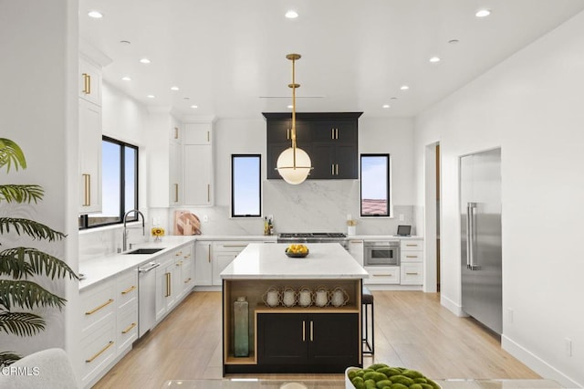 kitchen featuring white cabinets, a center island, sink, and light hardwood / wood-style flooring