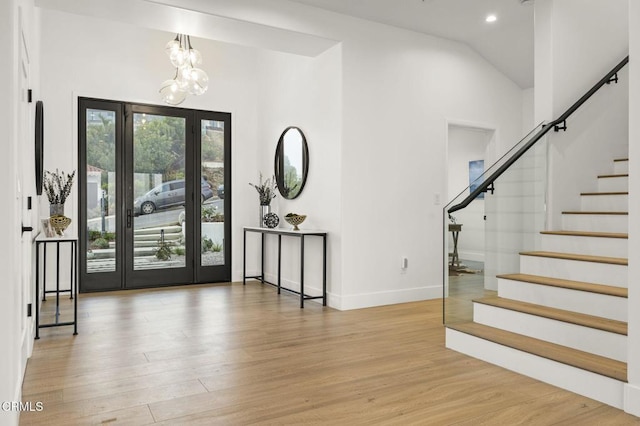 entryway featuring a chandelier, light hardwood / wood-style floors, and vaulted ceiling