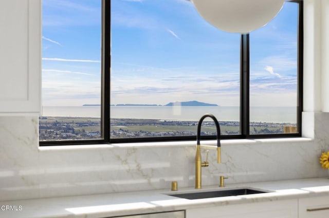 kitchen with a water view, white cabinetry, and sink