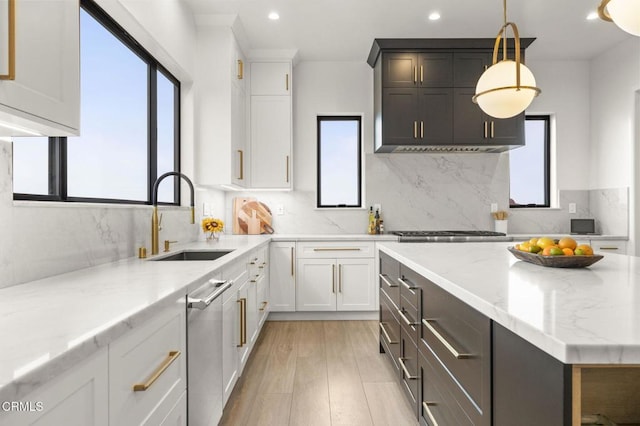 kitchen with light stone counters, sink, pendant lighting, light hardwood / wood-style flooring, and white cabinetry