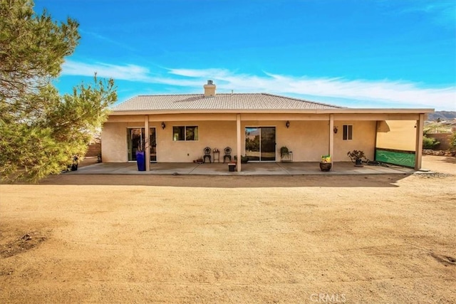 8550 Condalia Ave, Yucca Valley, CA 92284 - rear view of house featuring a chimney, a patio, a tile roof, and stucco siding