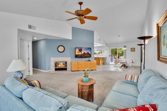 carpeted living room with a tile fireplace, ceiling fan, and lofted ceiling