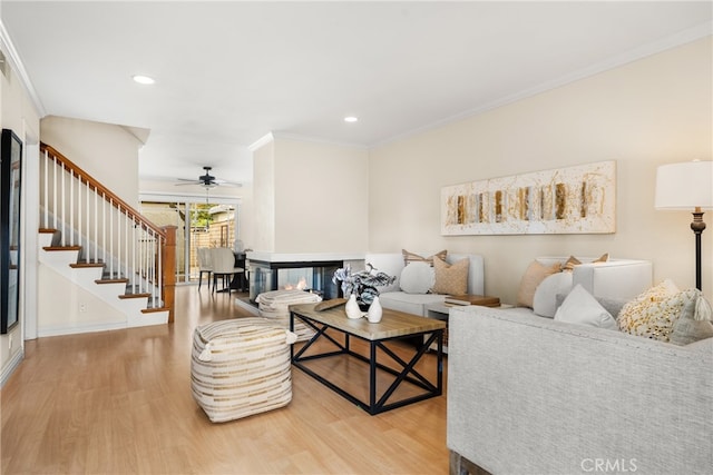 living room featuring a multi sided fireplace, hardwood / wood-style floors, and crown molding