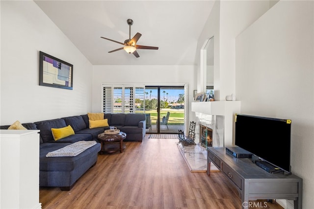 living room featuring vaulted ceiling, wood finished floors, a high end fireplace, and a ceiling fan