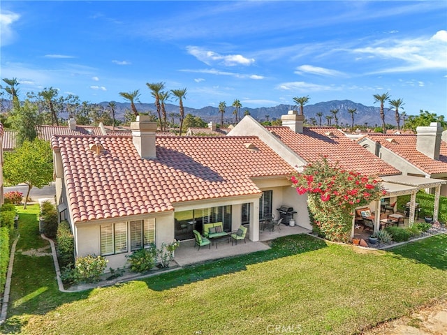 back of property featuring a yard, a patio area, a tile roof, and a mountain view