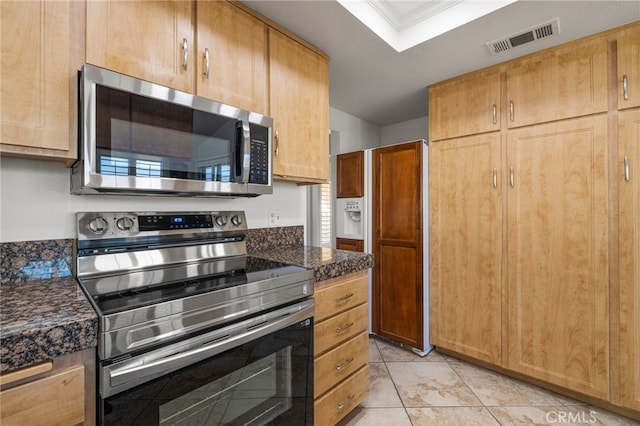 kitchen with visible vents, dark stone countertops, a tray ceiling, stainless steel appliances, and light tile patterned flooring