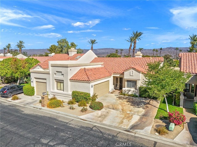 mediterranean / spanish house with a garage, a tile roof, and a mountain view