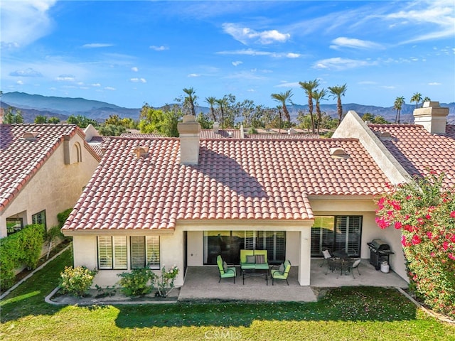 rear view of house featuring a patio area, a tiled roof, a chimney, and stucco siding