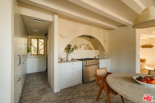 kitchen with tasteful backsplash, white cabinets, stainless steel stove, and decorative light fixtures