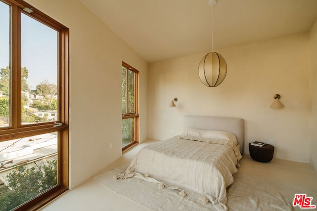 bedroom featuring multiple windows, light carpet, and vaulted ceiling