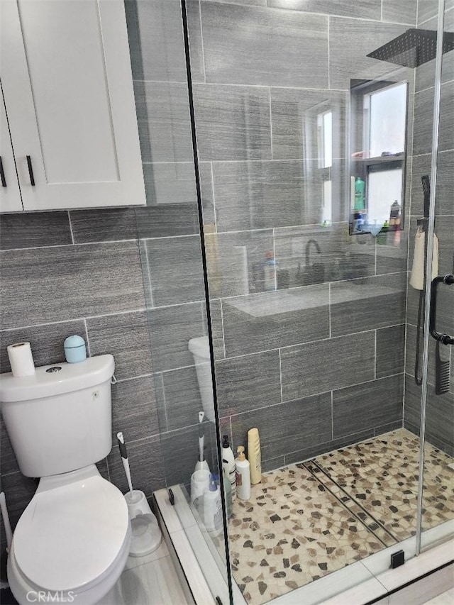 bathroom with an enclosed shower, tasteful backsplash, toilet, and tile walls