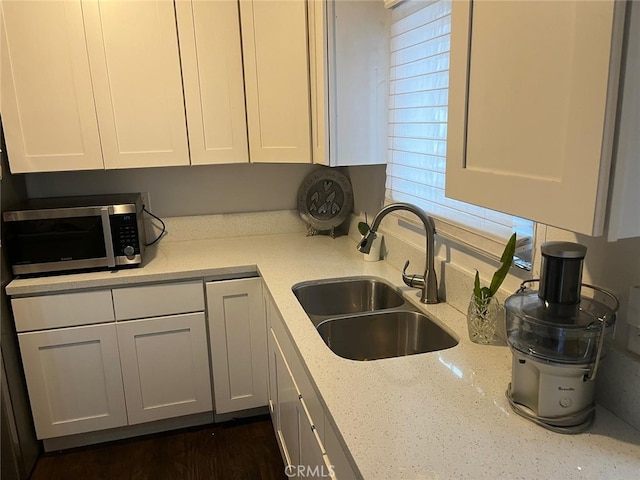 kitchen with light stone countertops, sink, and white cabinets