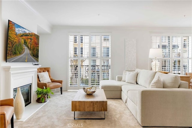 living area featuring a glass covered fireplace, light carpet, and crown molding