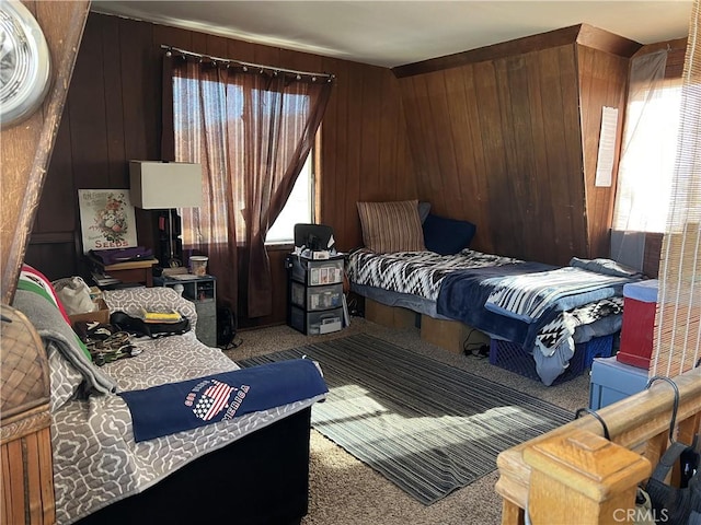 carpeted bedroom featuring multiple windows and wood walls