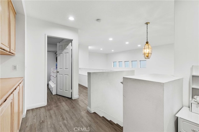 kitchen with kitchen peninsula, light brown cabinetry, pendant lighting, and light wood-type flooring